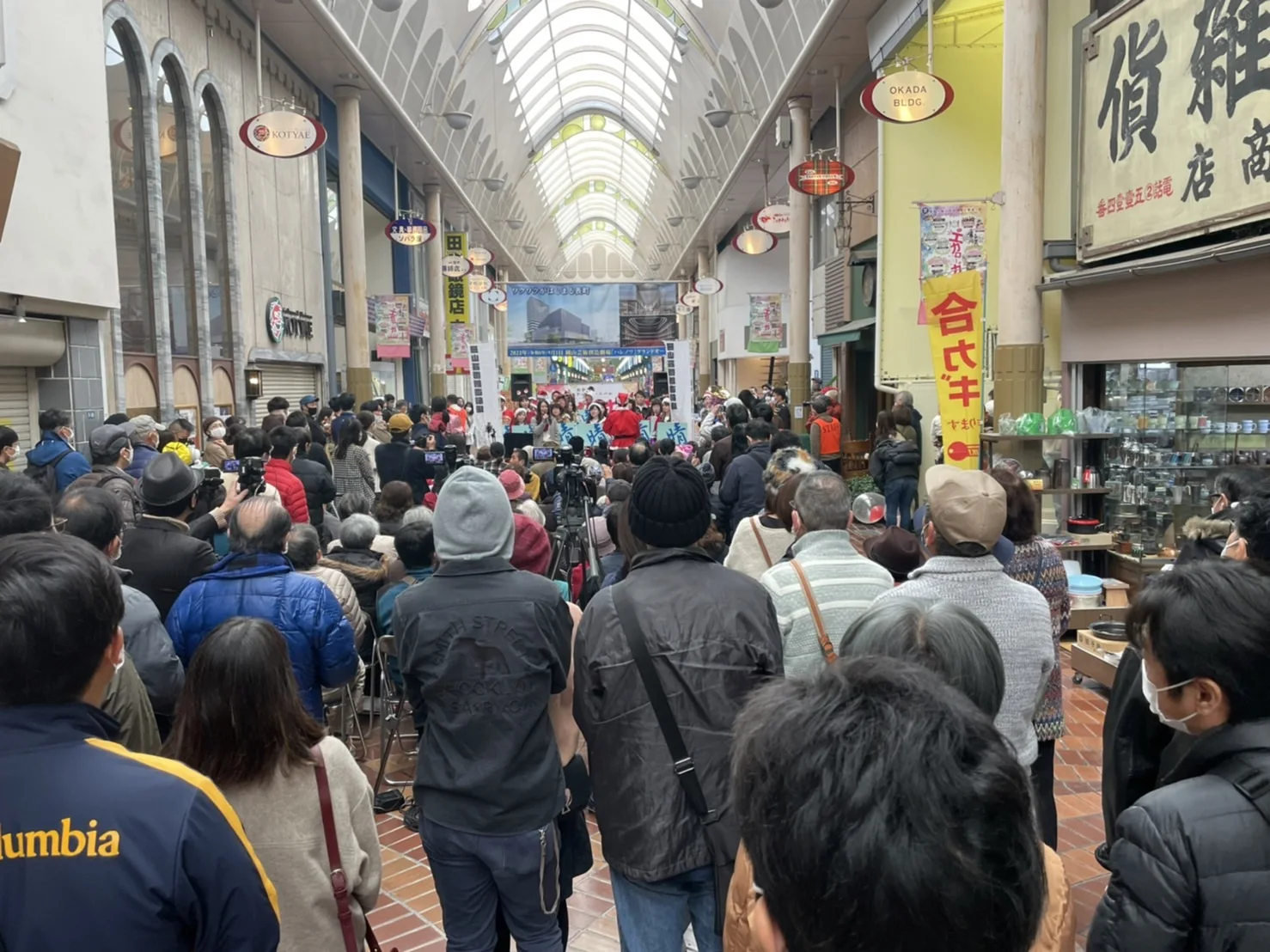 表町商店街のアーケードを埋めつくす大勢のお客さんと、奥のステージで演奏する吹奏楽団
