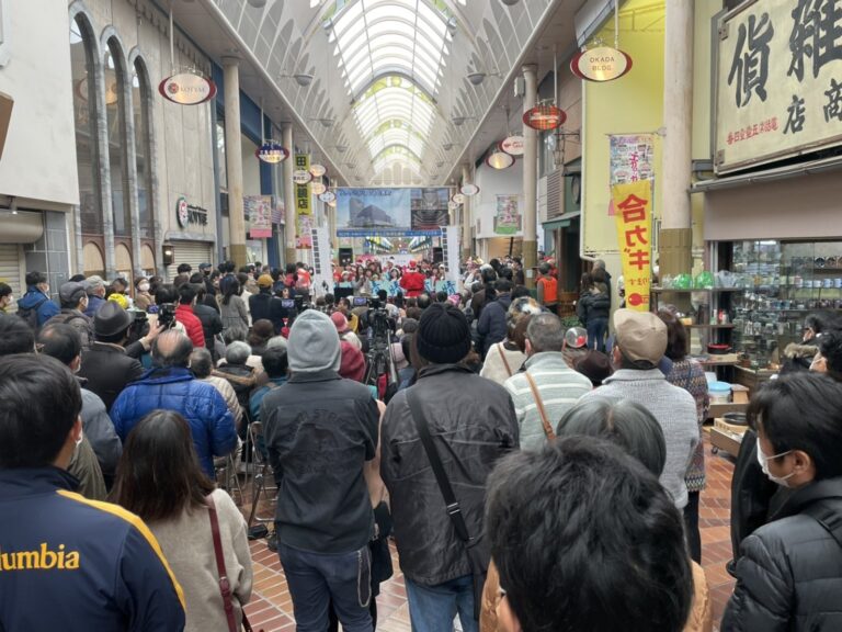 表町商店街のアーケードに大勢のお客さんが集まり、奥のステージの演奏を楽しむ様子（過去のイベント）